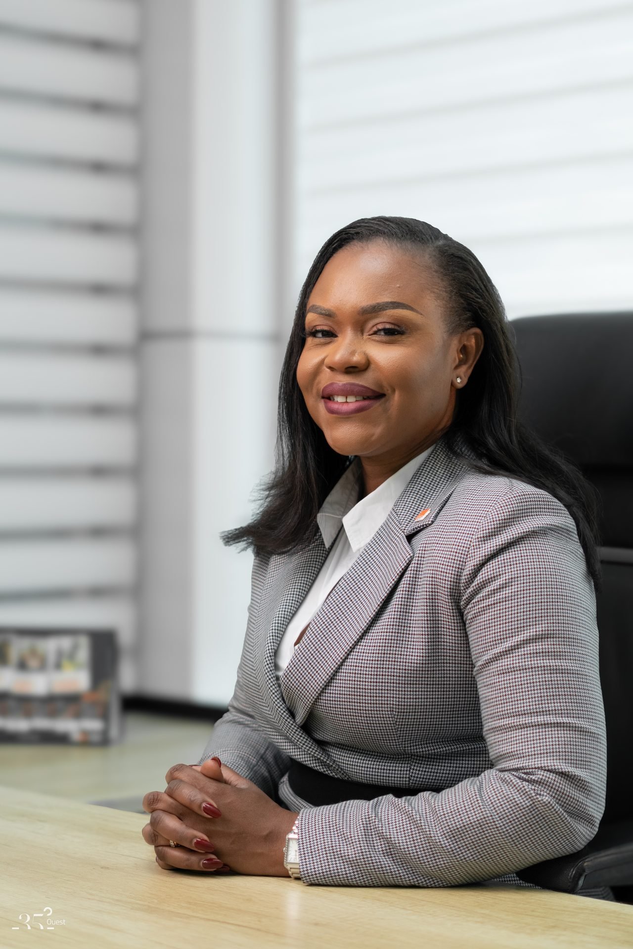Audrey Koffi Niamkey assise et souriante, en tenue grise.