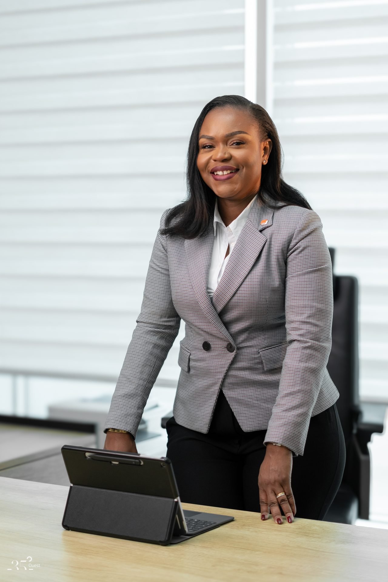 Audrey Koffi Niamkey debout à un bureau, une tablette à la main, en tenue grise.