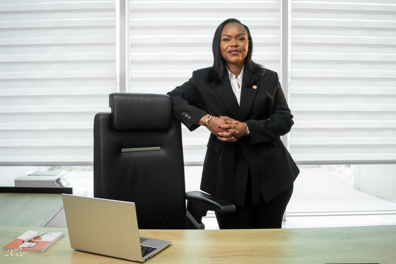 Audrey Koffi Niamkey debout près d’un fauteuil, dans un bureau, en tenue noire.