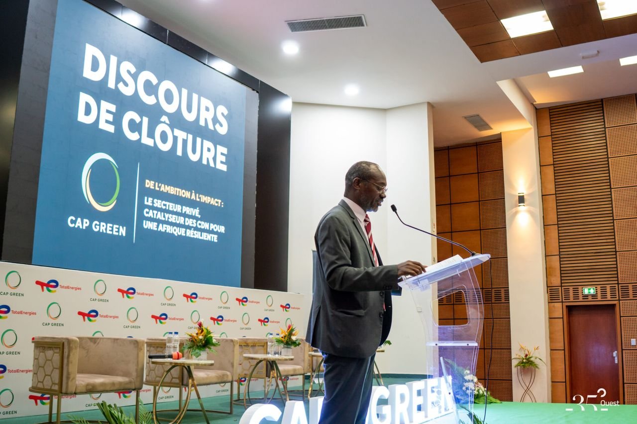 Un intervenant au pupitre lors du discours de clôture du forum CAP GREEN, devant un grand écran aux couleurs de l’événement.