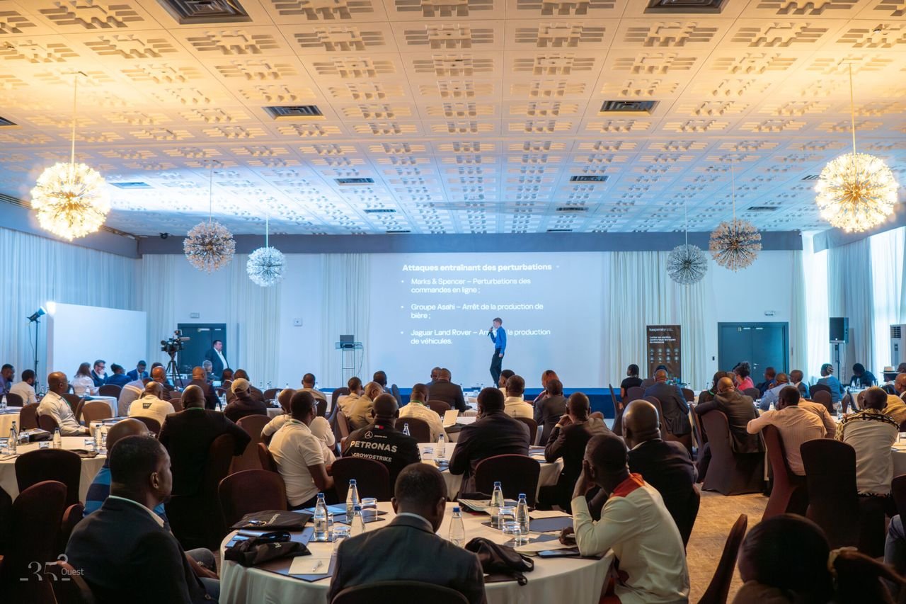 Salle de conférence de KNext Abidjan 2026 : le public assis à des tables rondes fait face à l’intervenant et à l’écran de présentation.